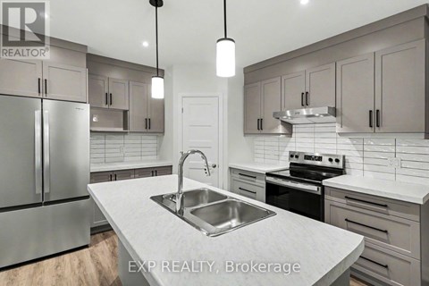 A modern kitchen with a stainless steel sink and refrigerator.