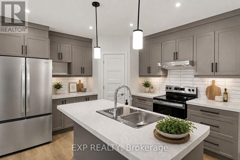 A modern kitchen with a stainless steel refrigerator and a central island with a sink.