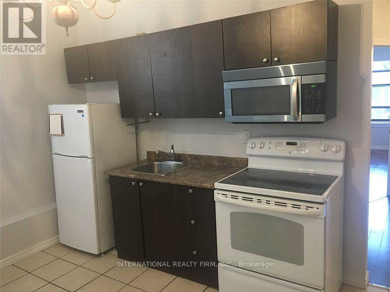 A kitchen with a white fridge, white oven, and black cabinets.