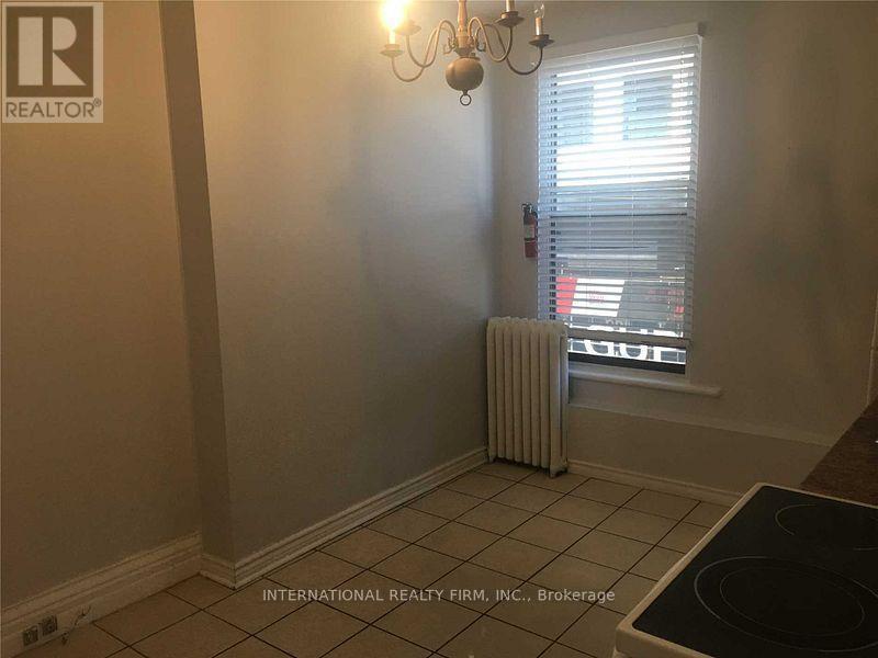 A room with a chandelier, a window with blinds, and a radiator.