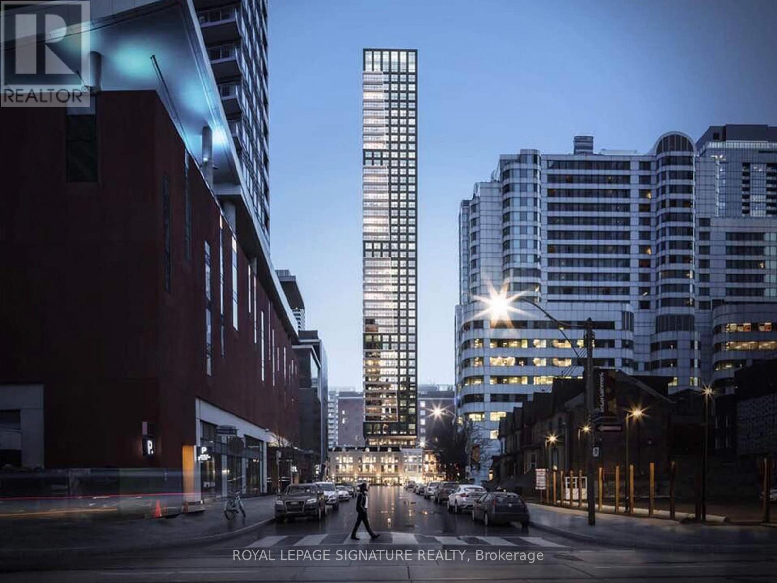 A city street with a tall building in the background at dusk.