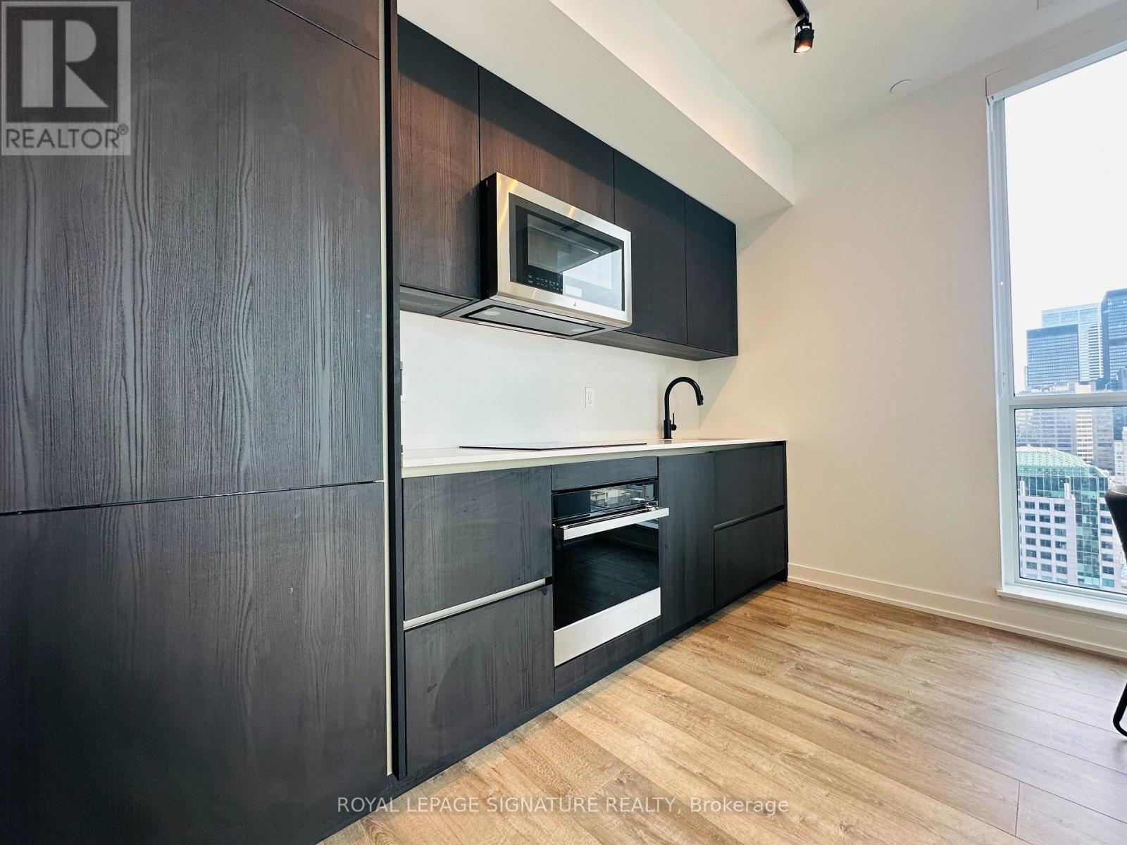 A modern kitchen with dark wood cabinets and a white countertop.