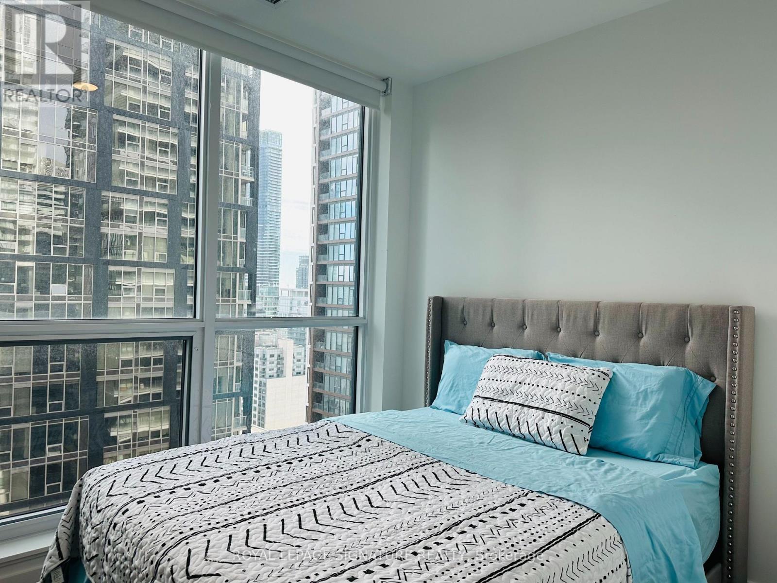 A bedroom with a large bed and a view of a city skyline.