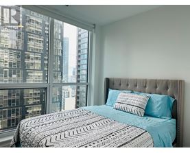 A bedroom with a large bed and a view of a city skyline.