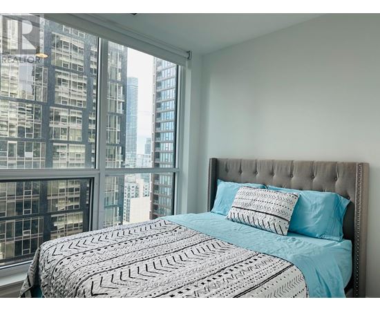 A bedroom with a large bed and a view of a city skyline.