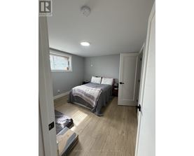 A bedroom with a bed, a window, and a door.