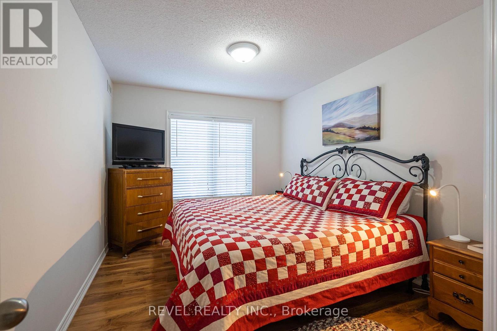 A bedroom with a bed, dresser, and television.