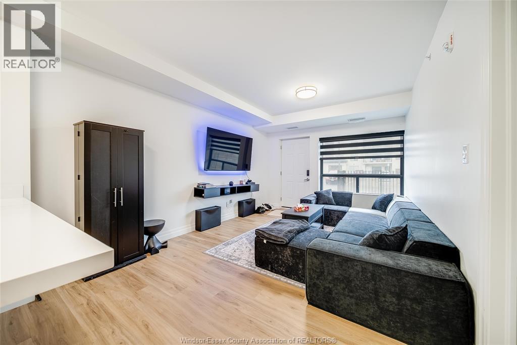 A living room with a black couch and a wooden floor.