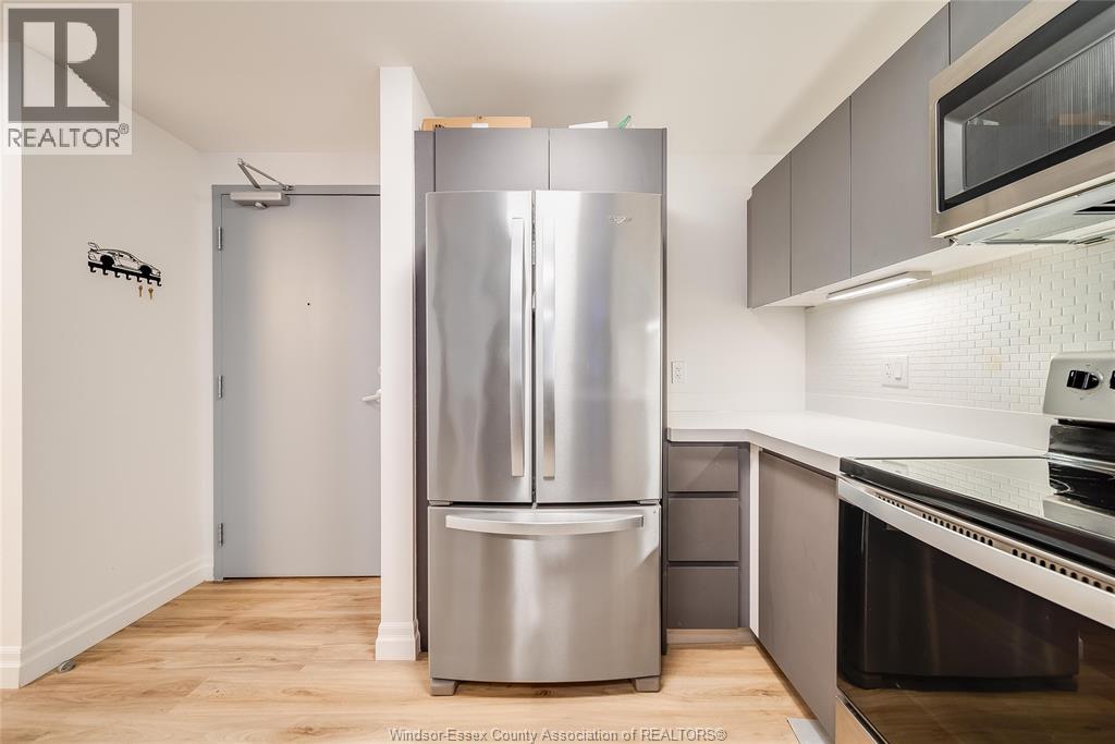 A kitchen with a stainless steel refrigerator and a microwave above the oven.