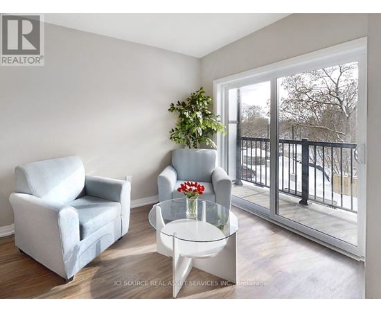 A living room with a grey couch, a white chair, and a glass table with a vase of flowers on it.
