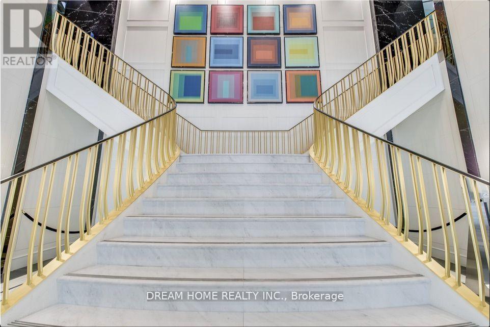 A staircase with a gold railing and a white wall with a colorful painting on it.