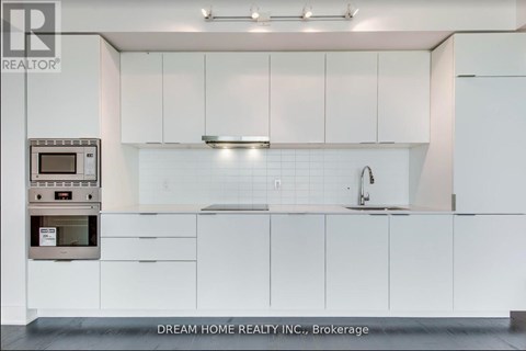 A modern kitchen with white cabinets and a microwave oven.