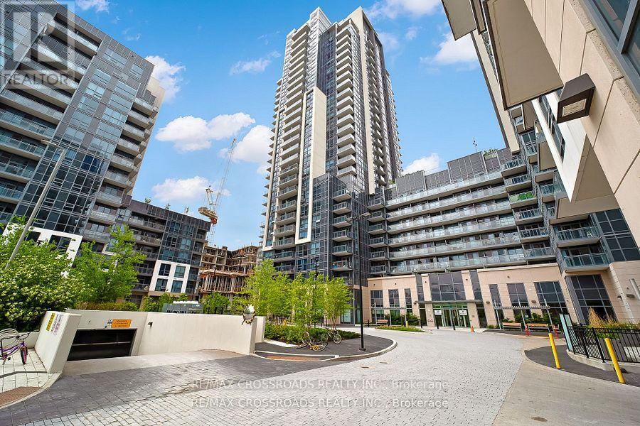 A modern building with a glass facade stands tall in the center of a paved courtyard.