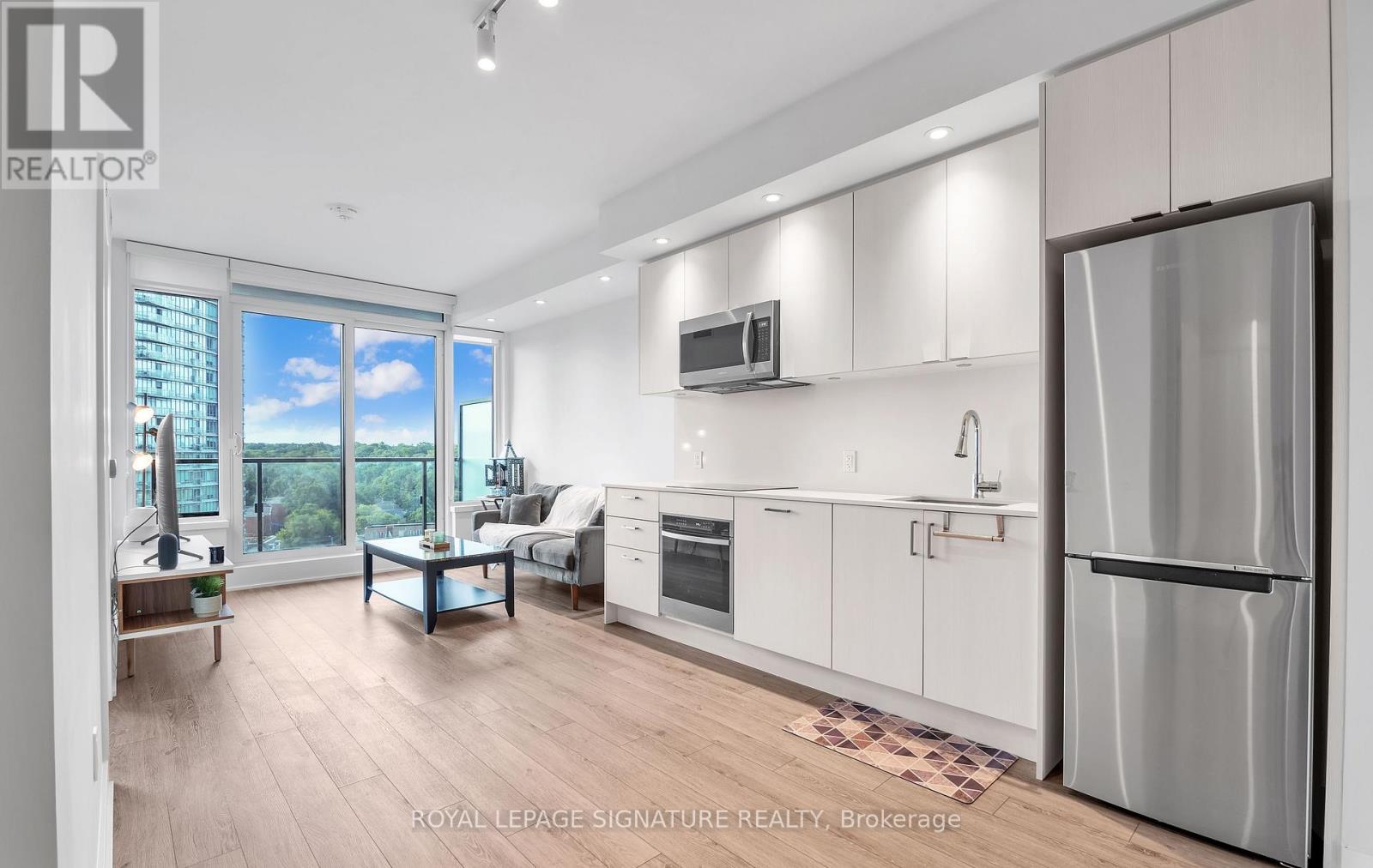A modern kitchen with white cabinets and a refrigerator.