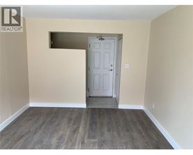 A room with a white door and wooden flooring.