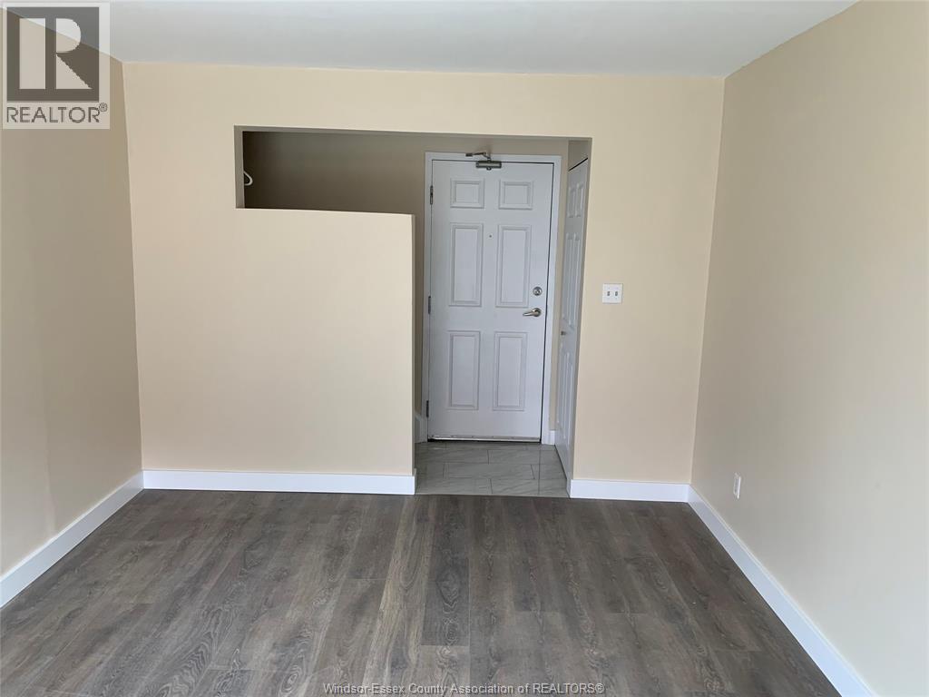 A room with a white door and wooden flooring.