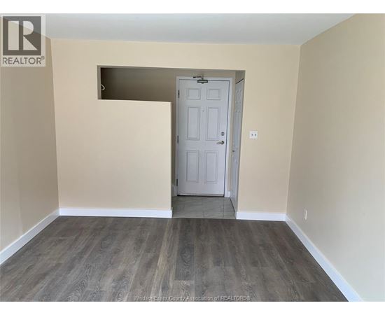 A room with a white door and wooden flooring.