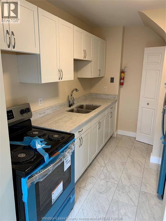 A kitchen with a blue stove top oven and white cabinets.