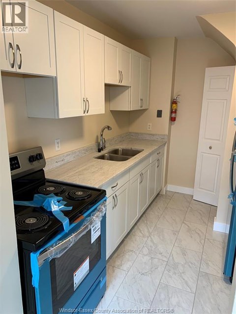 A kitchen with a blue stove top oven and white cabinets.