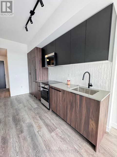 A modern kitchen with dark wood cabinets and a stainless steel sink.