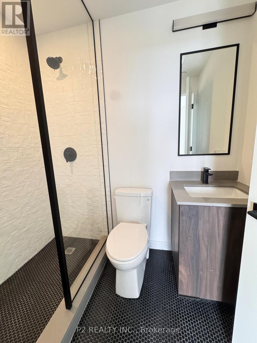 A white toilet in a small bathroom with a sink and mirror.