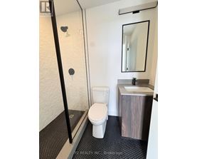 A white toilet in a small bathroom with a sink and mirror.