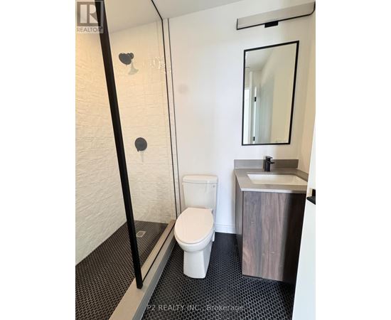 A white toilet in a small bathroom with a sink and mirror.