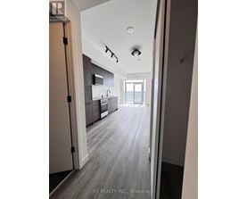 A hallway with a kitchen visible through the door.
