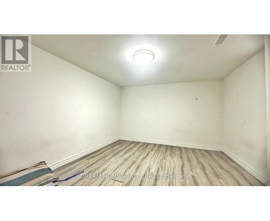 A room with wooden flooring and a ceiling light.