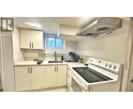 A white kitchen with a stove top oven and cabinets.