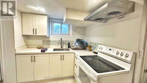 A white kitchen with a stove top oven and cabinets.