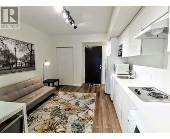 A modern kitchen with white cabinets and a floral rug on the floor.