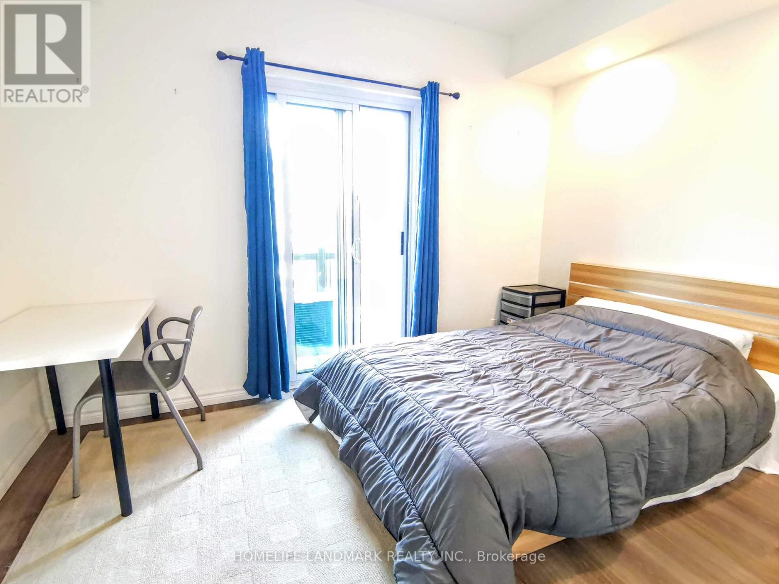 A bedroom with a bed, desk, and chair.