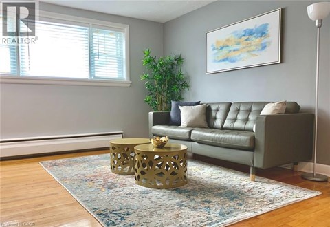 A living room with a grey couch, a yellow coffee table, and a painting on the wall.