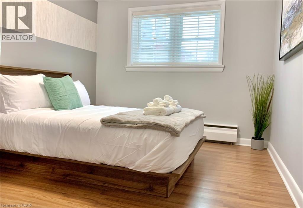 A bedroom with a bed, a nightstand, and a plant.
