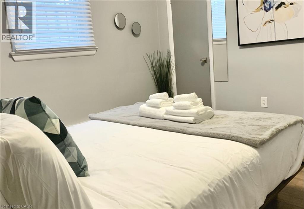 A bed with white sheets and a white blanket with towels on top.
