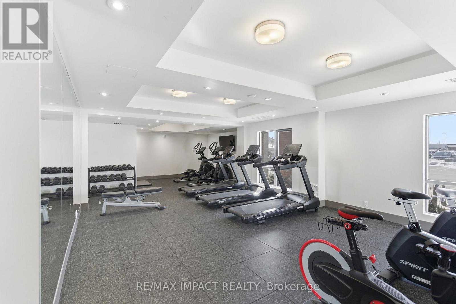A gym with a variety of equipment including treadmills, stationary bikes, and dumbbells.