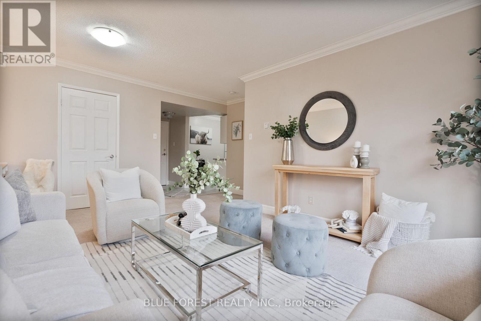 A living room with a glass coffee table and white furniture.