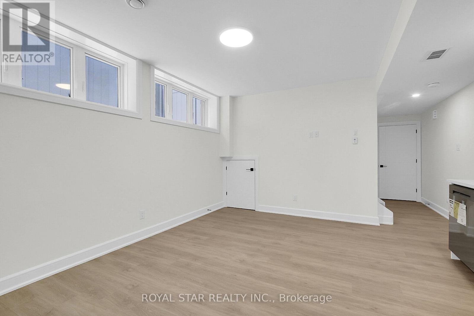 A white room with wood flooring and a window.