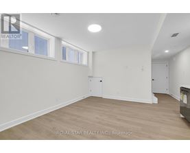 A white room with wood flooring and a window.
