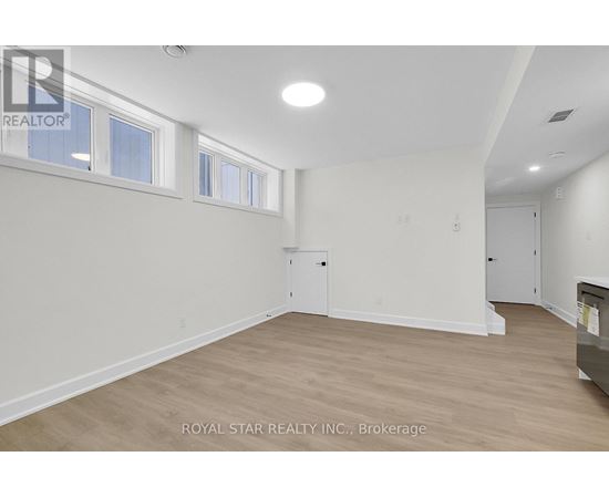 A white room with wood flooring and a window.