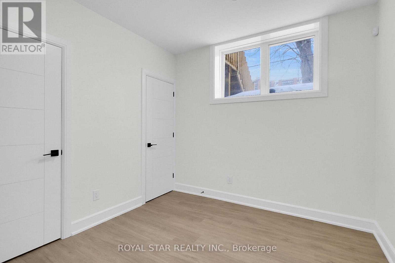 A grey building with a glass door and a snowy sidewalk.