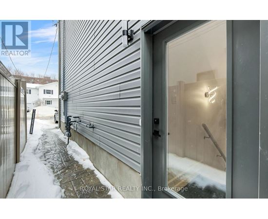 A grey building with a glass door and a snowy sidewalk.
