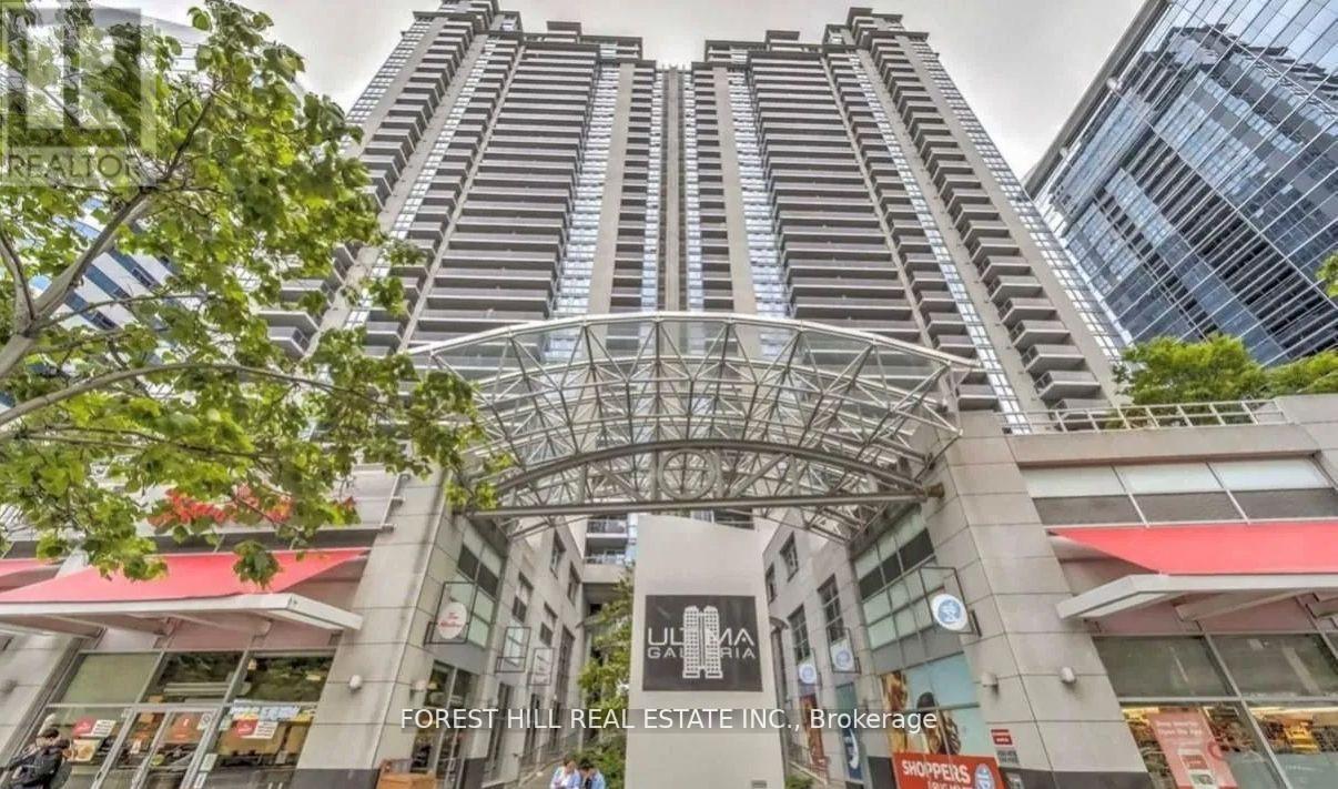 A tall building with a glass facade and a sign that reads "Forest Hill Real Estate Inc." in front of it.