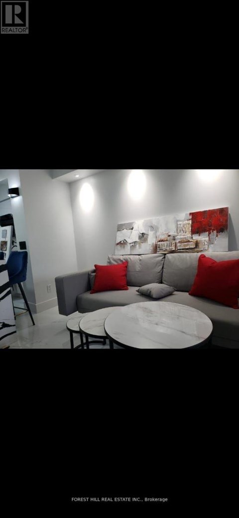 A modern living room with a grey couch and red pillows.