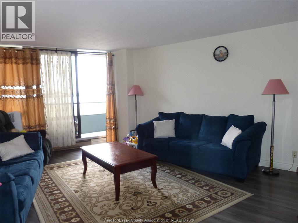 A living room with a blue couch, a wooden table, and a window with curtains.
