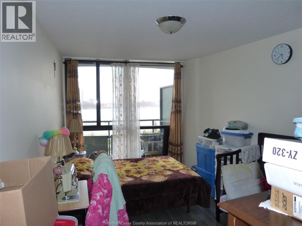 A bedroom with a bed, a desk, and a window with curtains.