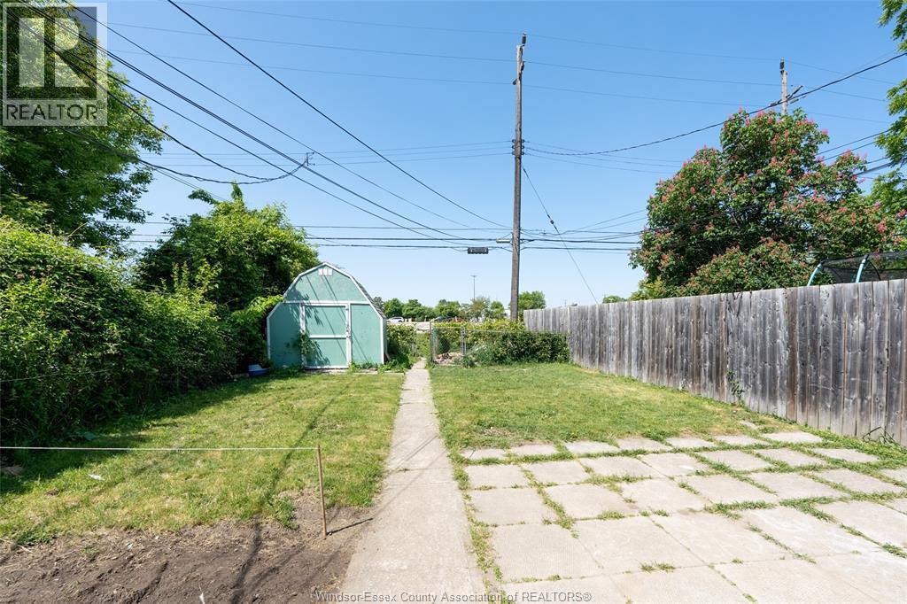 A green shed sits in a grassy area next to a wooden fence.