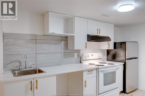 A kitchen with white cabinets and a stainless steel refrigerator.