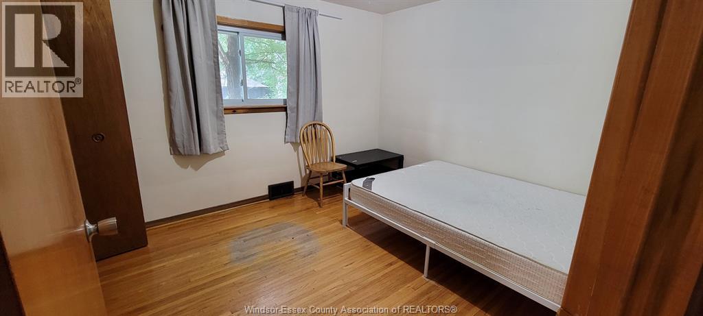 A bedroom with a bed, chair, and window.